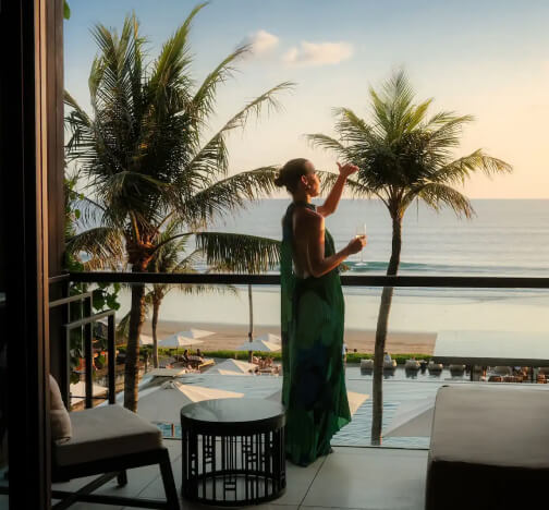Woman on a resort balcony overlooking a palm-lined beach, from World of Hyatt, an Antavo loyalty customer