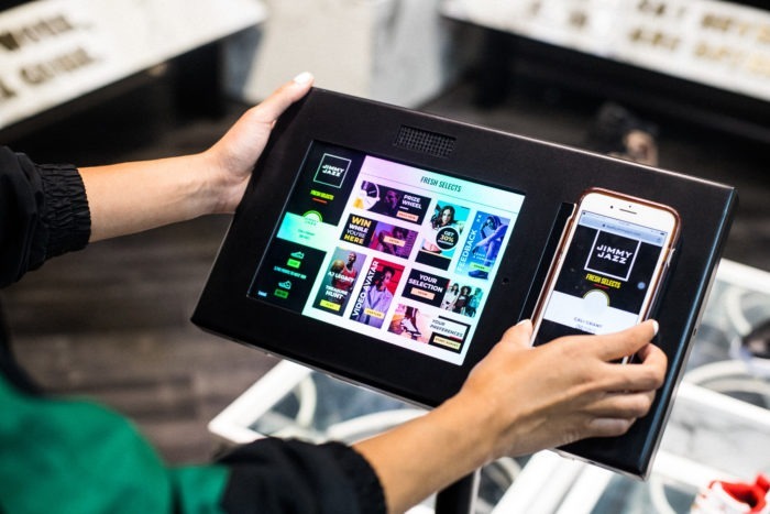 Customers at Jimmy Jazz can sign up for the Fresh Selects Loyalty Program using their phone. Then the phone interacts with the tablet, showcasing additional information or displaying the customer’s rewards.
